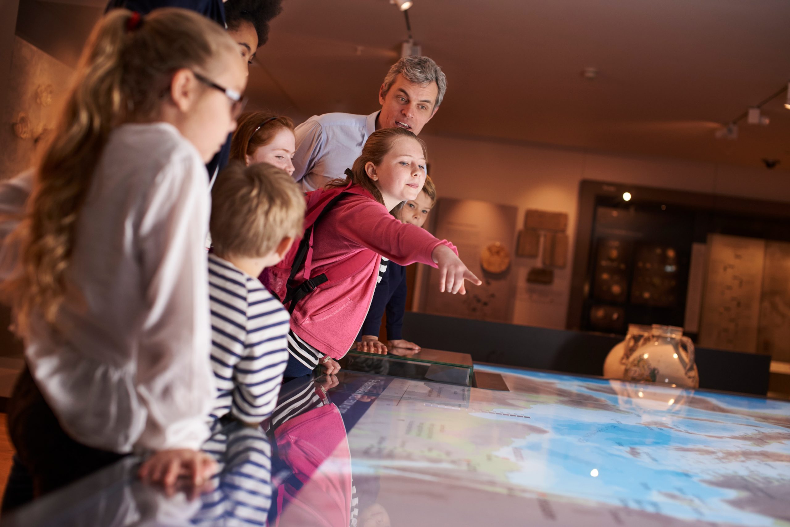 Pupils On School Field Trip To Museum Looking At Map